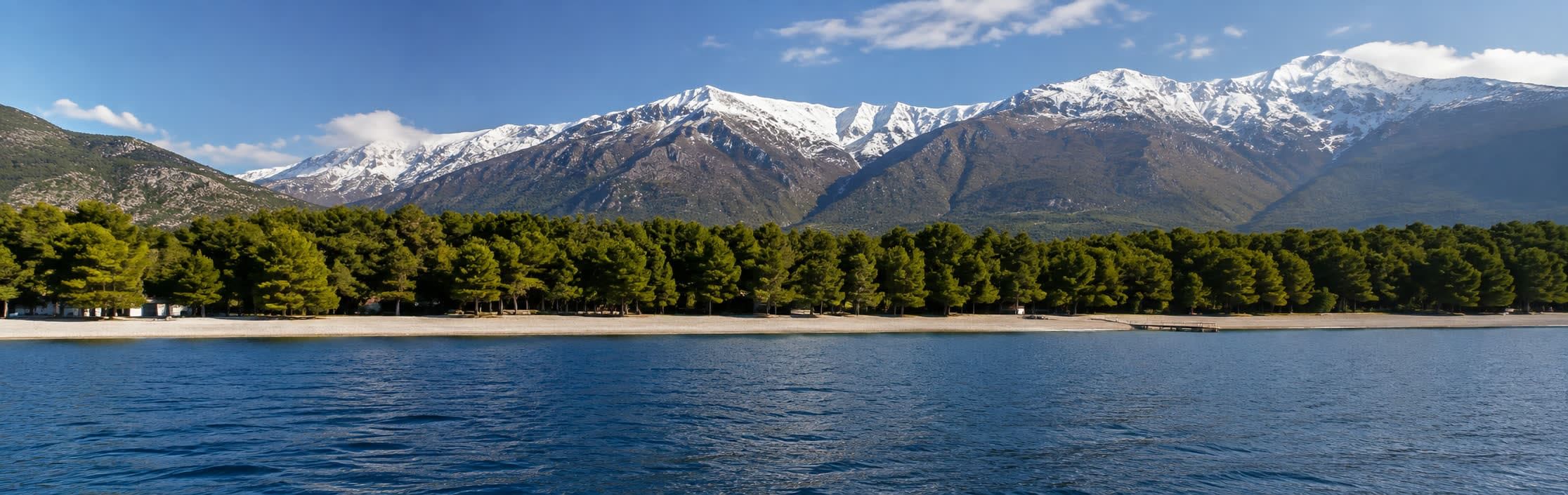 Snow-capped peaks above pine forest and the sea in Albania